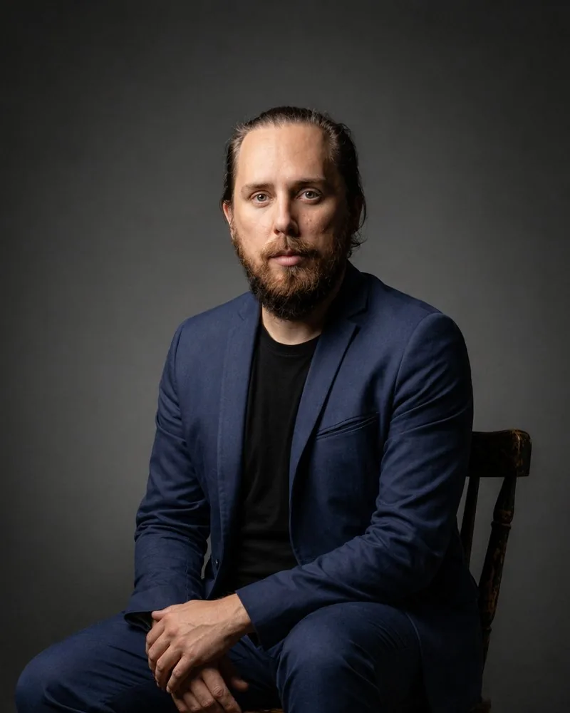 Retrato de Luiz Thomann, psicólogo, sentado de terno azul